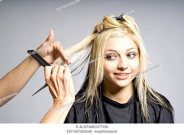 Hairdresser cutting hair of woman of nervous or unsure girl