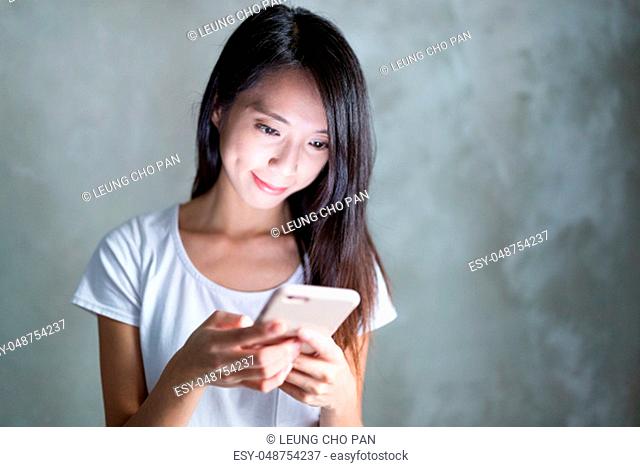 Young Woman use of mobile phone over grey background