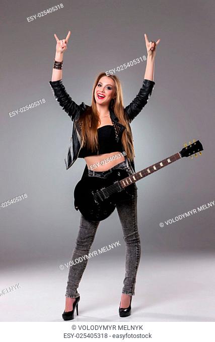 Beautiful girl with long hair and guitar in rock style on a gray background