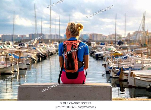 Young woman sitting with her back bag relaxed in the harbor