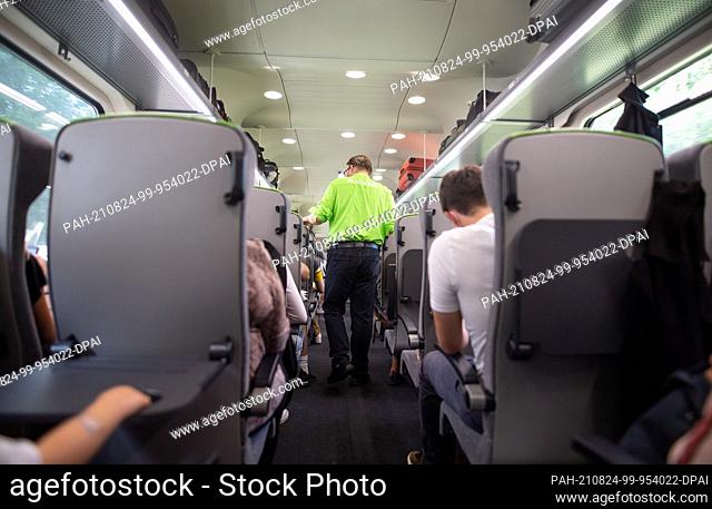 24 August 2021, Hamburg: A train attendant walks through a Flixtrain during a journey from Hamburg to Berlin and checks tickets