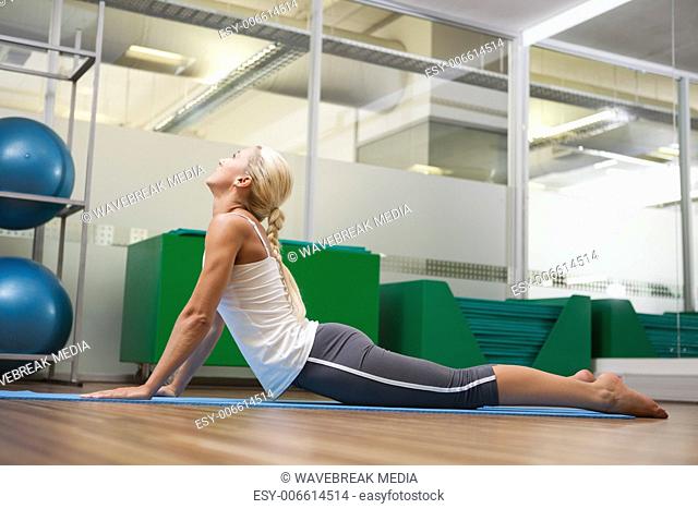 Side view of woman stretching her back in fitness studio