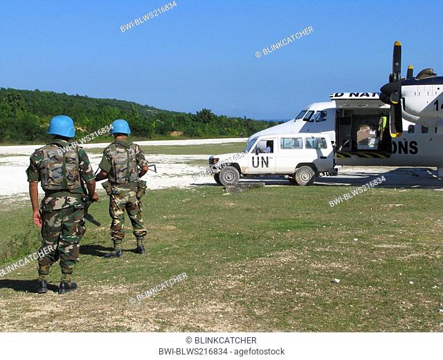 Soldiers of the 'United Nations Stabilisation Mission in Haiti' secure UN aircraft with machine gun and assault rifle next to unpaved runway, Haiti, Grande Anse