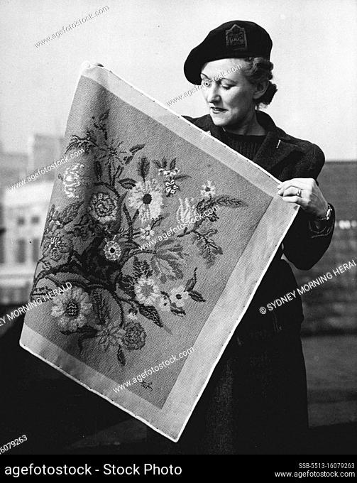 Bundles For The U.S. -- Mrs. Keeping, a W.V.S. worker, admires a contribution made by Queen Mary, in the form of a floral chair seat embroidered in ""gros point