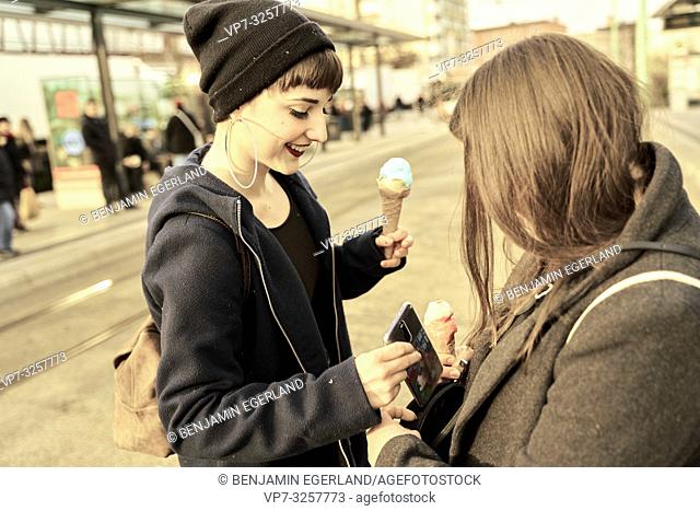 woman with ice cream grabbing phone of friend, in city Cottbus, Brandenburg, Germany
