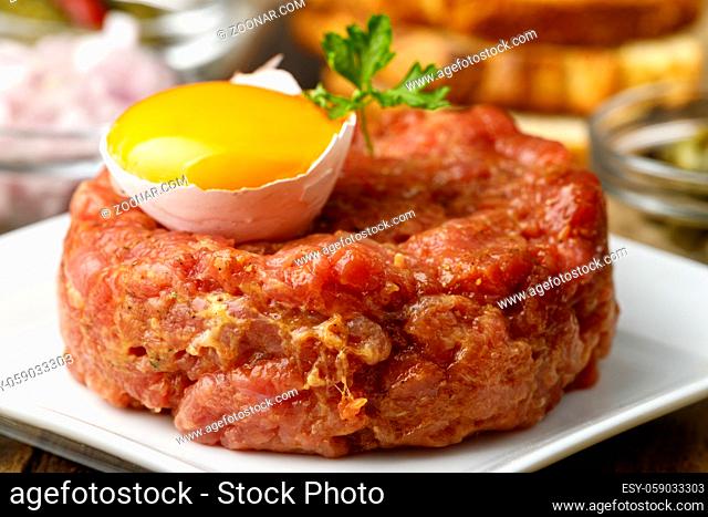 steak tartare with open egg on wood