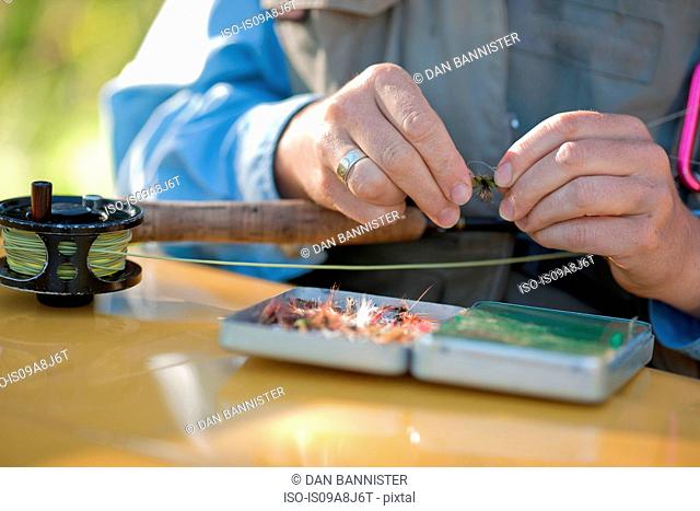 Mature woman preparing bait for fly fishing, close up