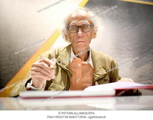 27 March 2019, Berlin: Hiding artist Christo signs his books ""Hidden Reichstag"", ""The Floating Piers"" and ""Barrels and The Mastaba"" in the flagship store...