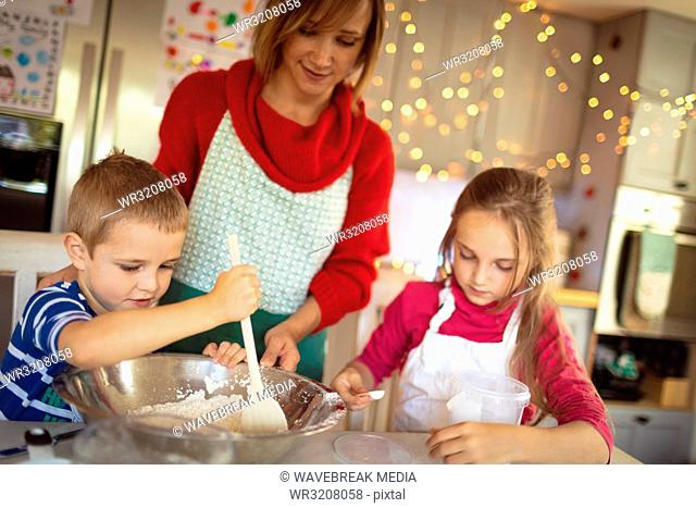 Mother and kids making Christmas cookies in kitchen