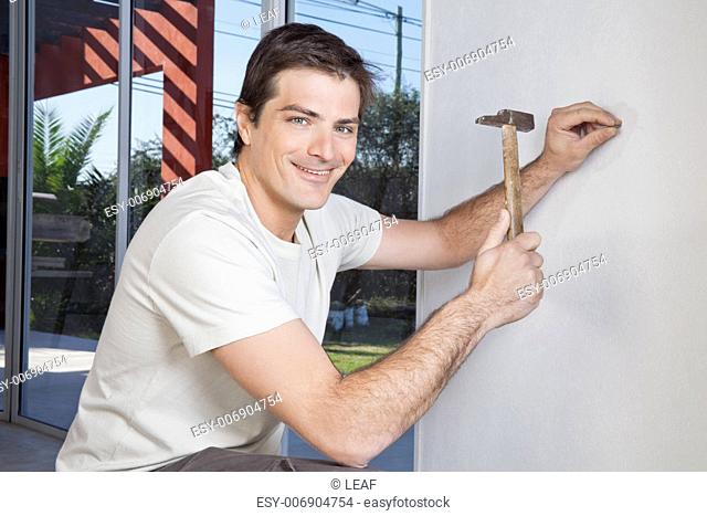 Nailing nail into wall with hammer Stock Photos and Images | agefotostock