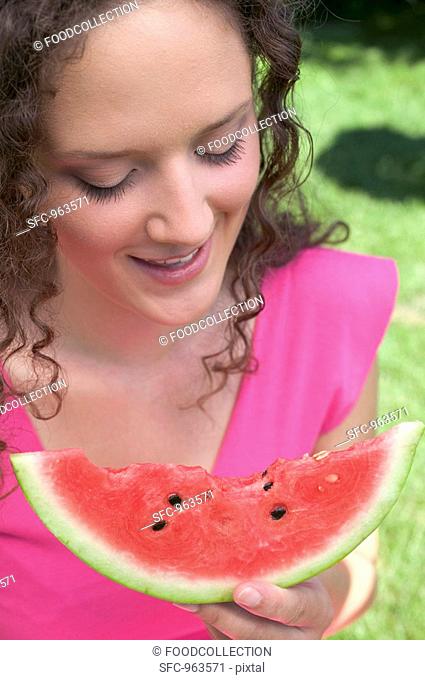 Woman holding slice of watermelon with bites taken