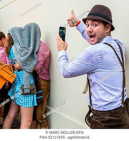 A visitor films a couple kissing each other underneath a cardigan during the Oktoberfest beer festival in Munich, Germany, 21 September 2014