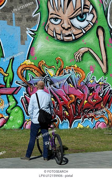 Man looking at graffiti painted on a wall in Reykjavik Iceland