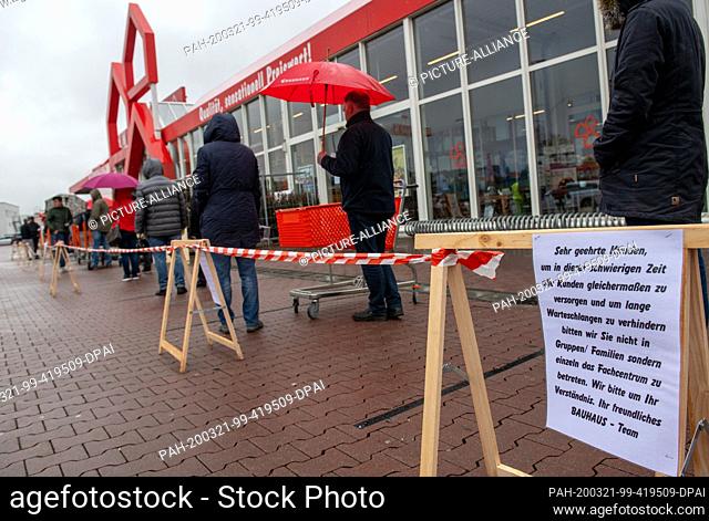 21 March 2020, Baden-Wuerttemberg, Ulm: People stand in a queue in front of a hardware store. Due to the exit restrictions in neighbouring Bavaria