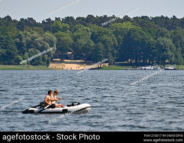 17 June 2021, Brandenburg, Storkow: Two people are on the move in an inflatable boat on Lake Storkow. With well over 30 degrees