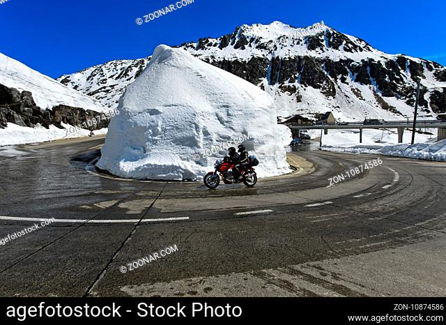 Motorradfahrer fährt in einer Haarnadekurvel um einen Schneekegel, Passtrasse über den Gotthardpass, Gotthardpass, Airolo, Kanton Tessin