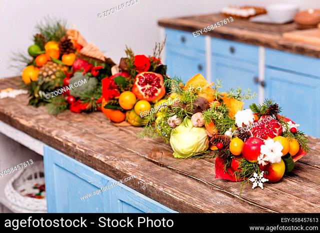 Nice original bouquets of edible fruits and vegetables. Eatable composition on wooden desk in the kitchen