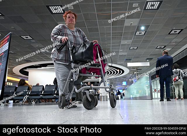 26 March 2020, Hessen, Frankfurt/Main: The homeless woman Tina is standing with her walker in the arrivals area of Terminal 1 at Frankfurt Airport