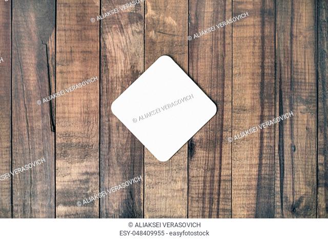Blank square beer coaster on wood table background. Responsive design mockup. Flat lay