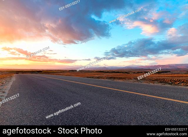 asphalt road with sunset glow in wilderness, xinjiang