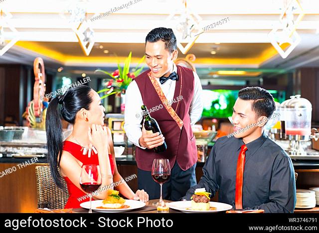 Waiter serving wine in Asian restaurant