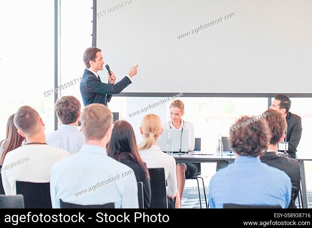 Speaker at business conference near white screen and audience