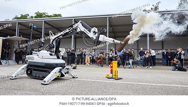 17 July 2019, Hamburg: Andre Kowalzik (l), deactivator, controls the manipulator ""Brokk 120 D"", which holds a smoking bomb dummy in the gripper arms