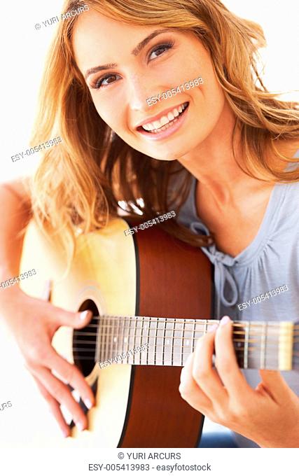 Smiling young woman holding her guitar and playing some music