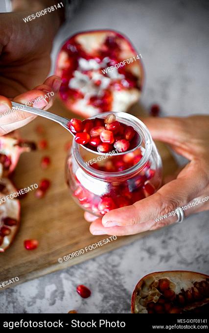 Hands of woman holding jar¶ÿof pomegranate seeds