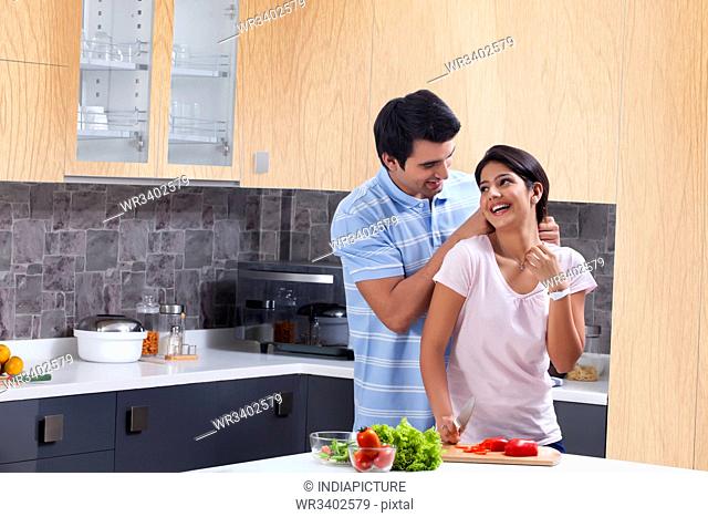 Loving man putting necklace on woman in kitchen