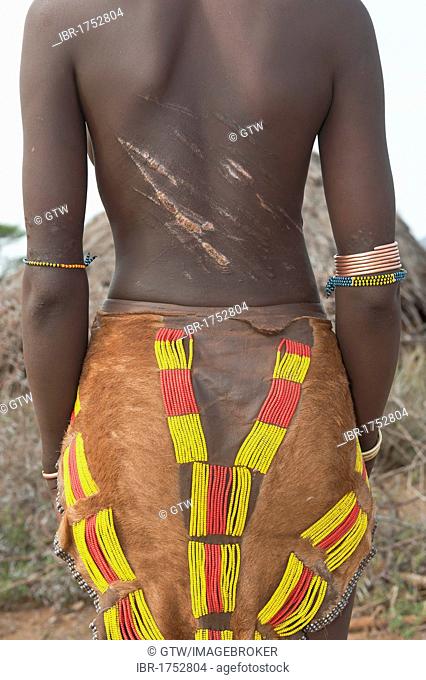 Young Hamar woman with traditional hairstyle with red clay and with scars and marks of being whipped on her back, Omo river valley, Southern Ethiopia, Africa