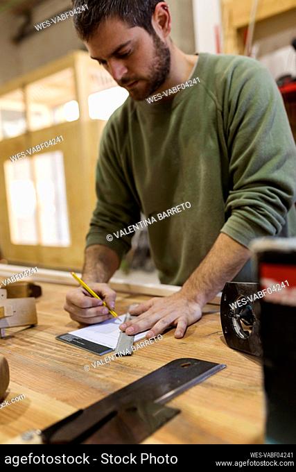 Male carpenter working at table in workshop