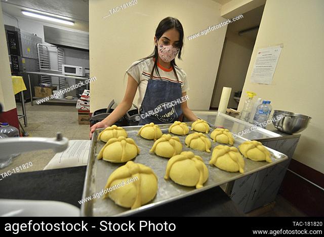 MEXICO CITY, MEXICO - OCTOBER 15: A woman wears face mask while holds a tray with Pan de muerto (bread of the dead), who is a type of bread baked with...