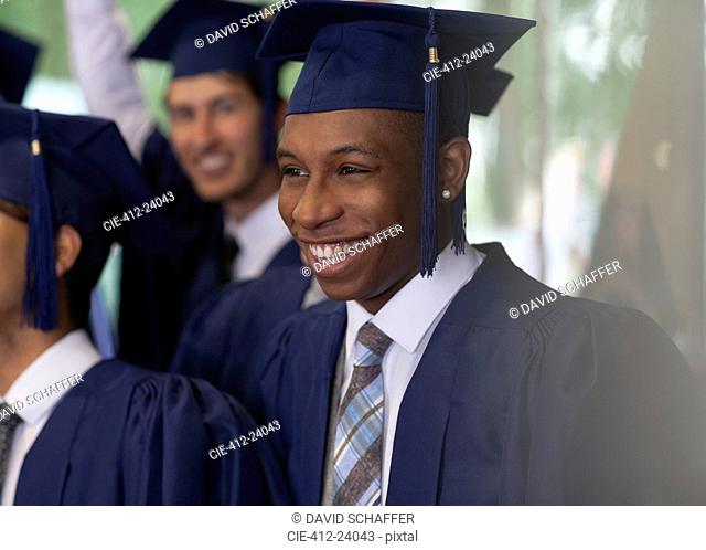 Smiling university students standing outdoors during graduation ceremony