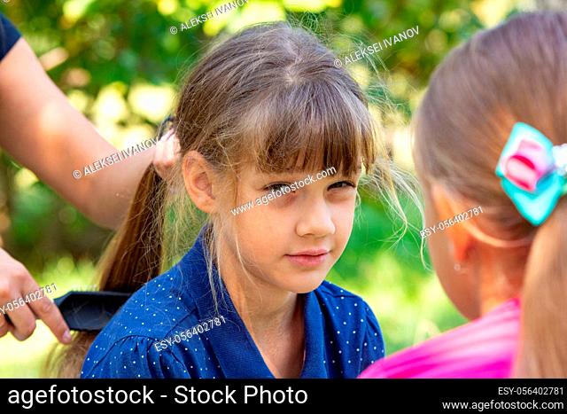 Girl trying to comb the girl’s tightly tangled hair