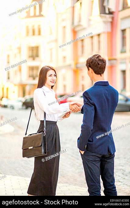 Business, partnership, technology and people concept - smiling businessman and businesswomen handshake for a business meeting outdoor.