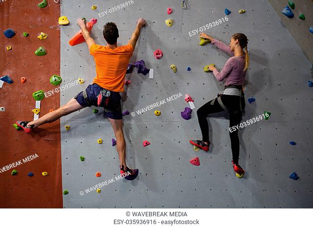 Rear view of athletes rock climbing in club