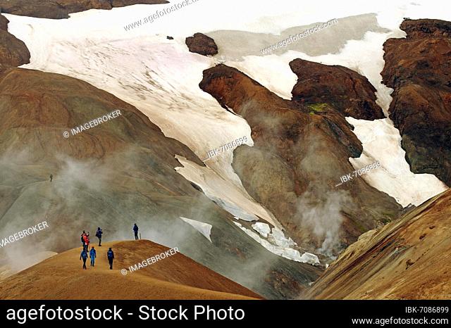 People on a hiking trail in front of snowfields, Geothermal landscapes and steam from hot springs, Kerlingarfjell, Iceland, Europe