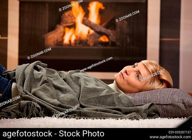 Woman resting at home lying on floor in front of a fire place