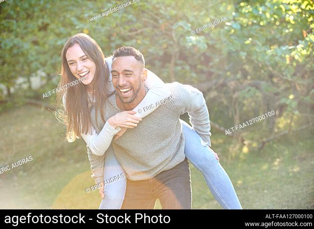 Smiling young man giving piggyback ride to his partner