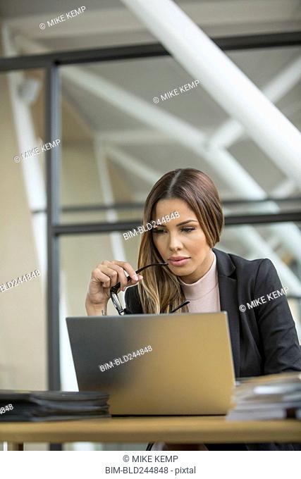 Pensive Mixed Race businesswoman using laptop