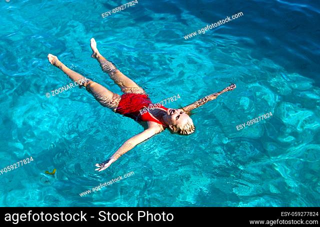young woman in a red bathing suit swimming in the blue sea in Tahiti