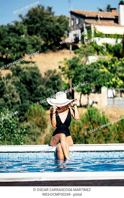 Pretty woman in a swimsuit sunbathing at the pool side