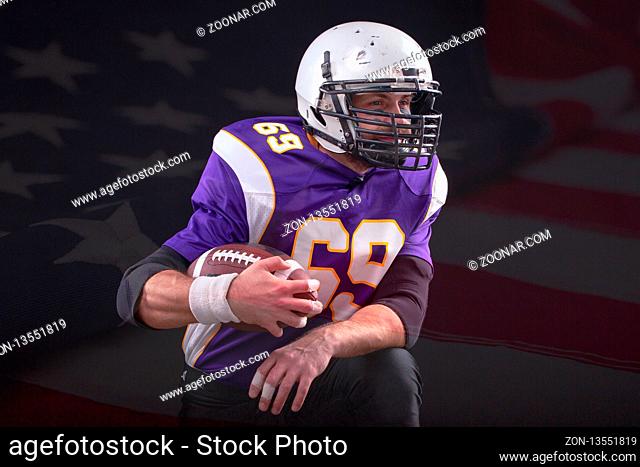 Close up portrait of American Football Player posing in studio wearing violett uniform with US flag on background