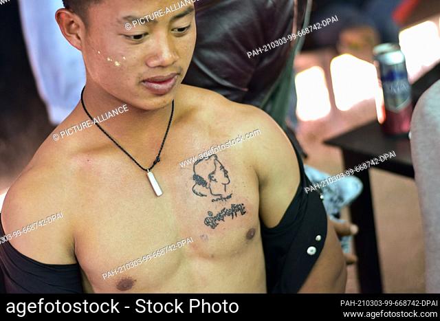 02 March 2021, Myanmar, Nyaung Shwe: A young man wears a tattooed portrait of Aung San Suu Kyi, the ousted head of Myanmar's government, on his chest