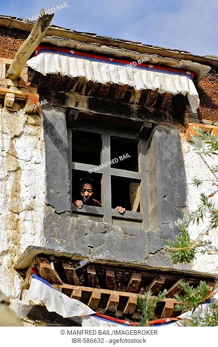 Tibetan woman looks through a window, Palcho Monastery or Pelkor chode or Shekar, Gyantse, Tibet
