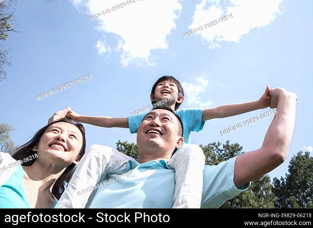 Family in park with son on father&rsquo;s shoulders