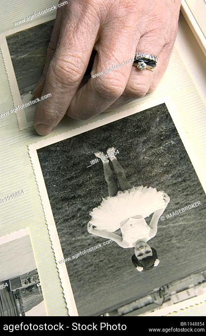 Hand resting on photo album, photo of young ballet dancer, memories