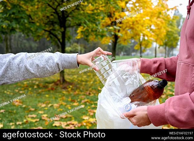 Hands of man holding plastic bag and boy putting bottle in it