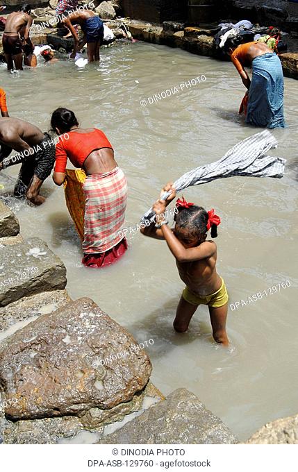 A girl child worker wash clothes in dirty waters at Dharavi in Bombay now Mumbai ; Maharashtra ; India